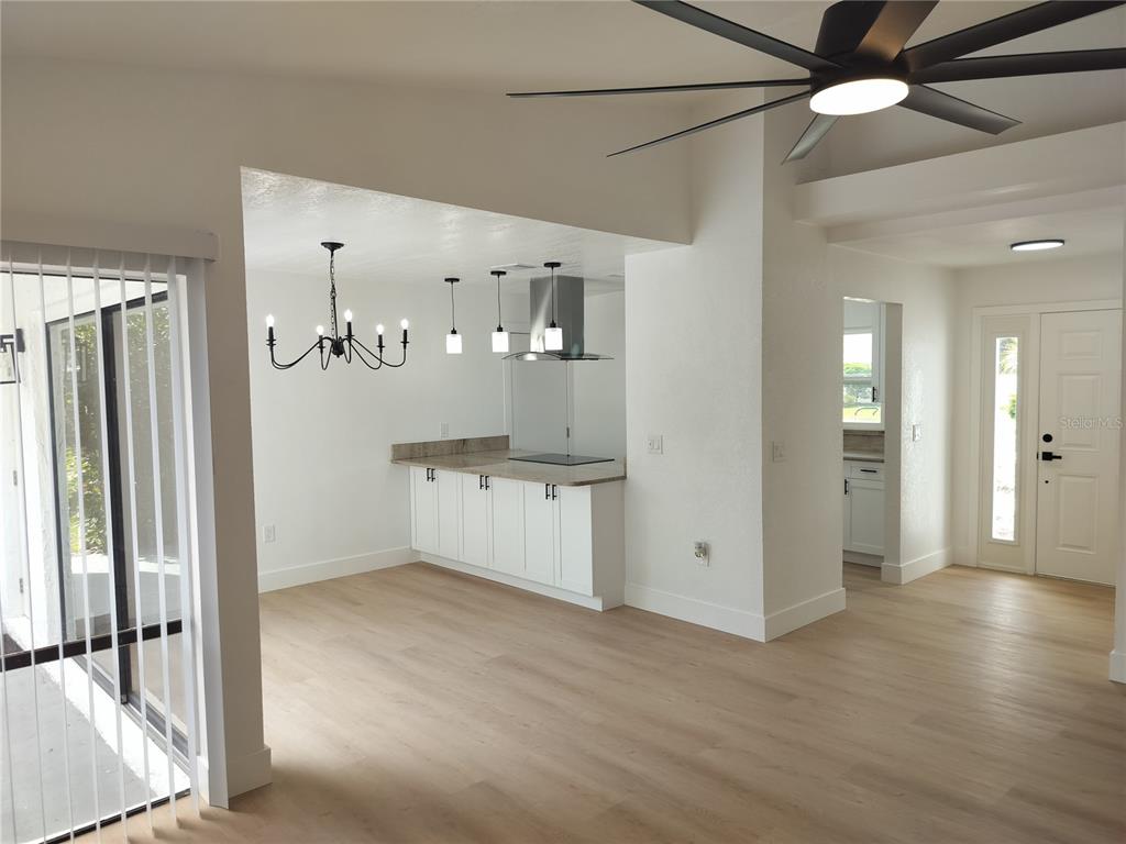 A kitchen with white cabinets and a stainless steel range hood overlooks a dining area — 2661 WARMSPRINGS WAY, PALM HARBOR, FL