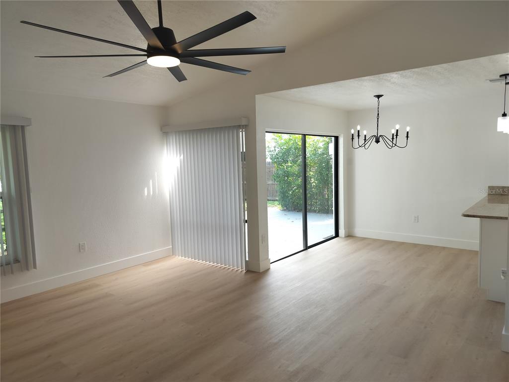 An open-concept living and dining area features light wood-look flooring, a ceiling fan, and sliding doors — 2661 WARMSPRINGS WAY, PALM HARBOR, FL
