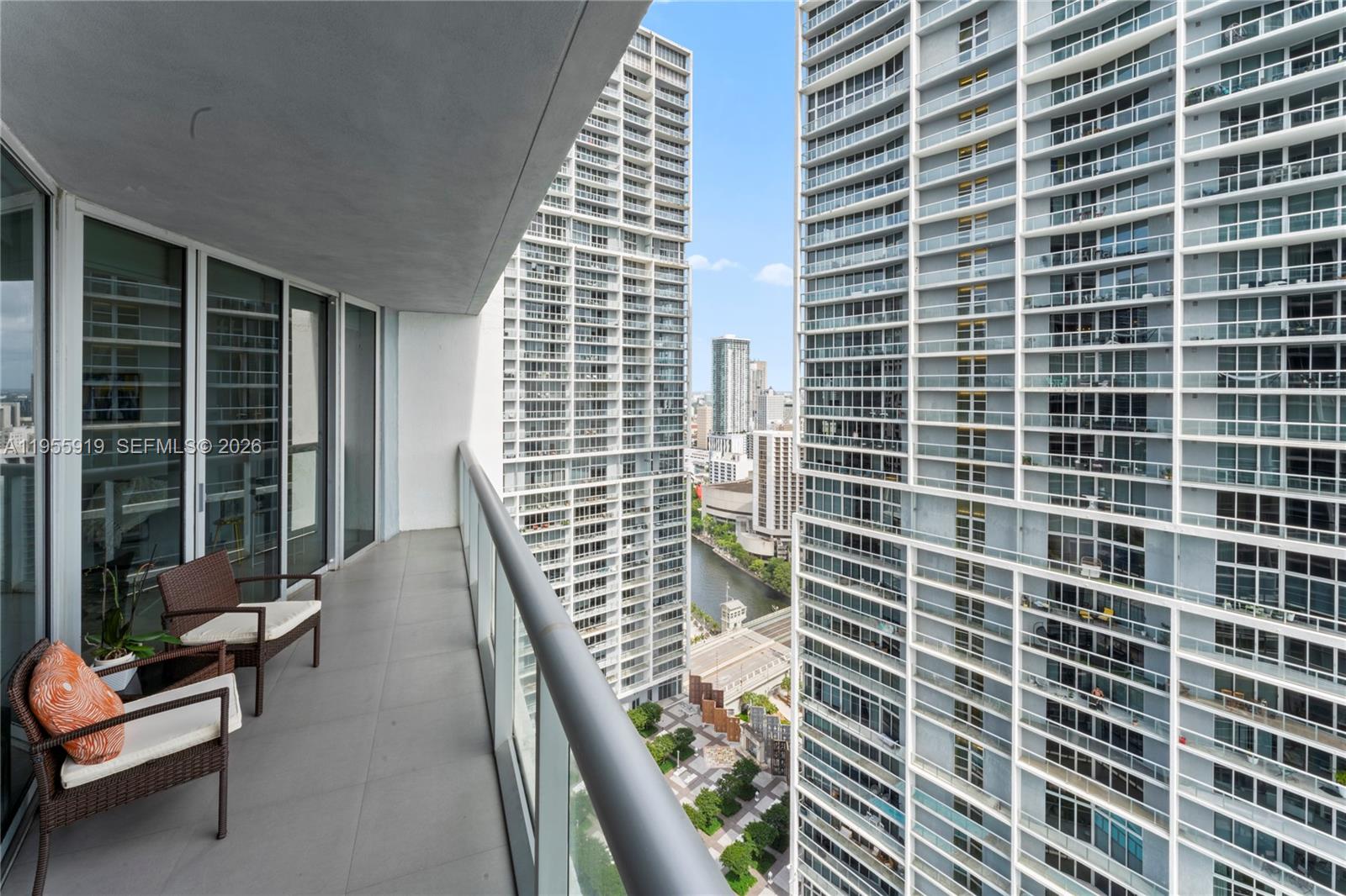 A high-rise balcony with two chairs overlooks a city canal and surrounding apartment towers — 495 Brickell Ave # 3208, Miami FL 33131, MIAMI, FL