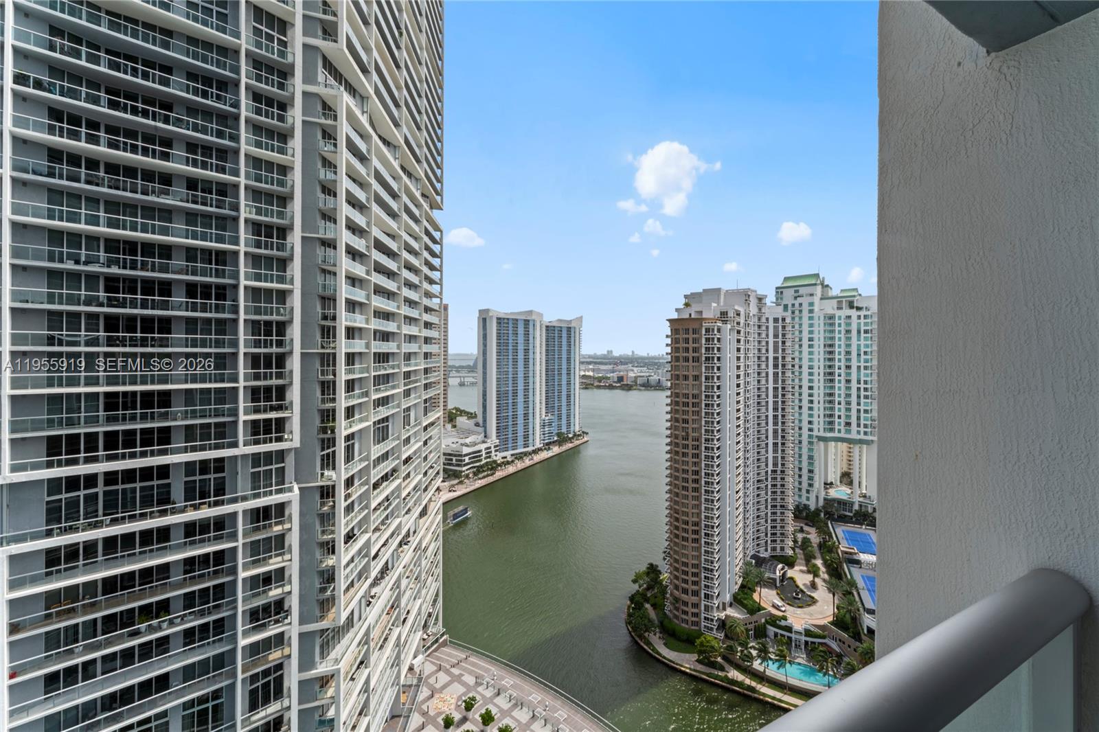 A high-angle view from a balcony overlooks a waterway surrounded by tall residential skyscrapers — 495 Brickell Ave # 3208, Miami FL 33131, MIAMI, FL