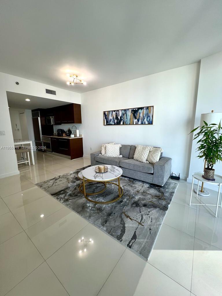 A living room with a gray sofa, marble coffee table, and an open kitchen — 495 Brickell Ave # 3208, Miami FL 33131, MIAMI, FL
