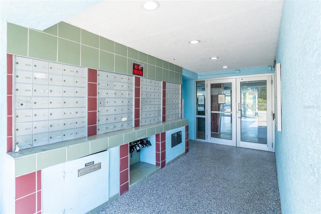 An indoor mailroom features rows of metal mailboxes, a trash chute, and glass entry doors — 3315 58TH AVENUE S UNIT 512, ST PETERSBURG, FL