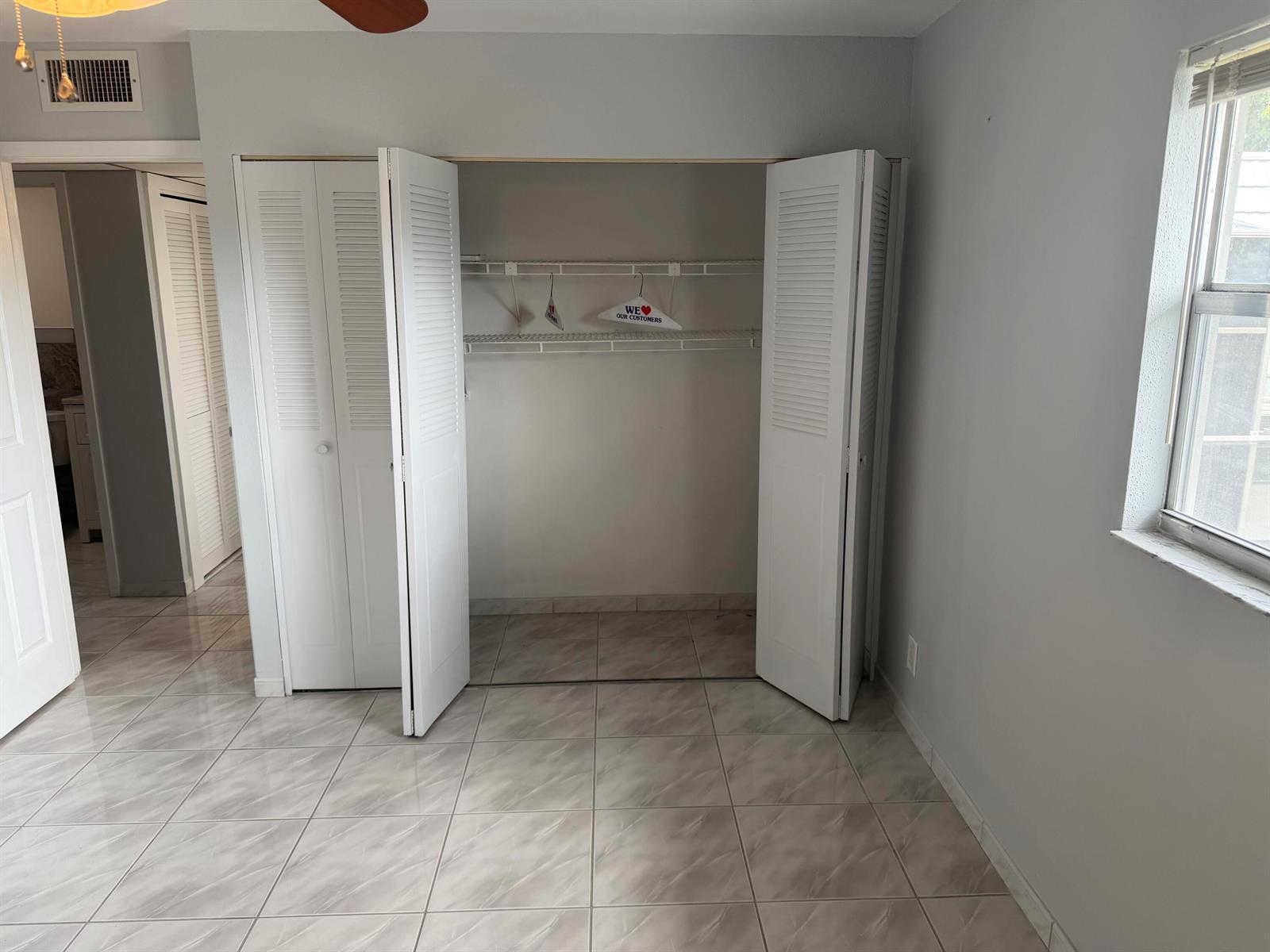 A room with light-colored tile flooring, gray walls, and an open closet with white louvered doors — 373 Monaco H, # H, Delray Beach FL 33446, DELRAY BEACH, FL