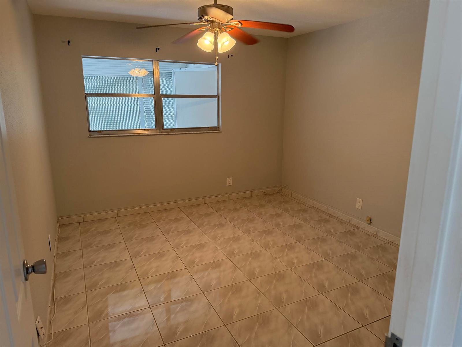 An empty bedroom features light-colored tile flooring, a ceiling fan, and a window — 373 Monaco H, # H, Delray Beach FL 33446, DELRAY BEACH, FL