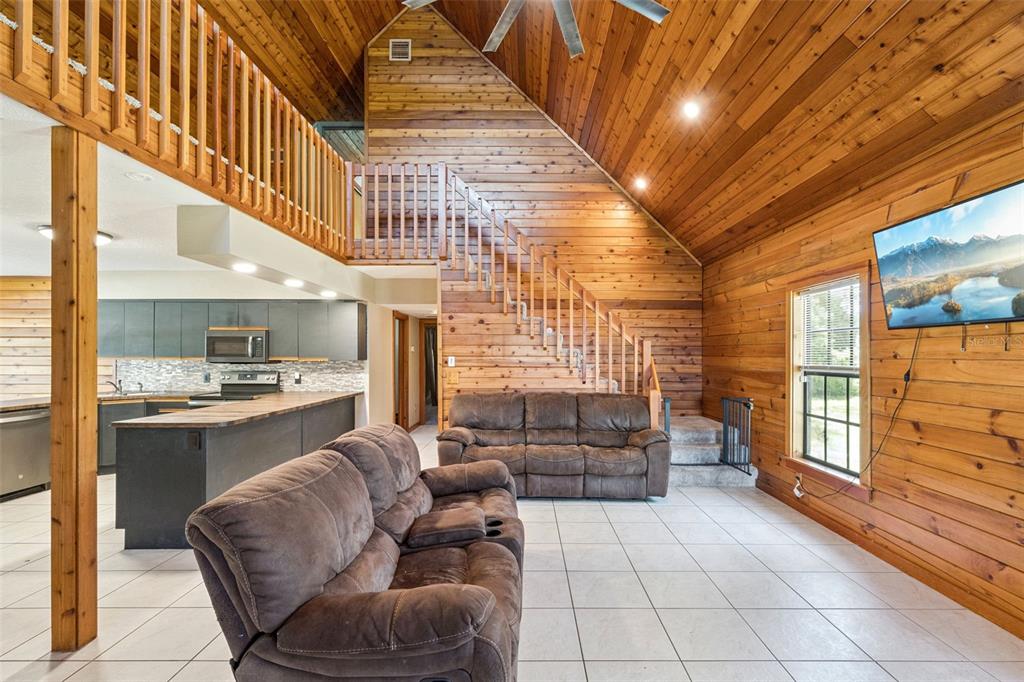 A blue two-story house with a stone fire pit in the grassy backyard — 25911 ABERDOVEY AVENUE, SORRENTO, FL