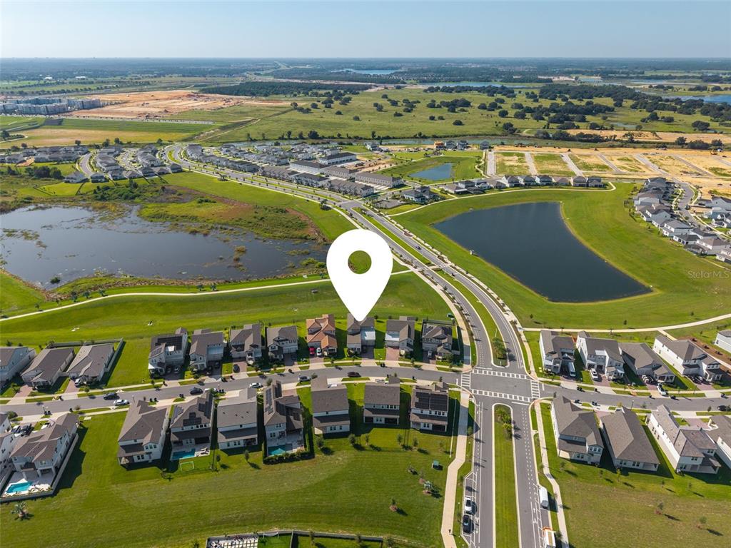 An aerial view shows a suburban neighborhood with houses, ponds, and surrounding undeveloped land — 5211 CITRUS LEAF BOULEVARD, WINTER GARDEN, FL