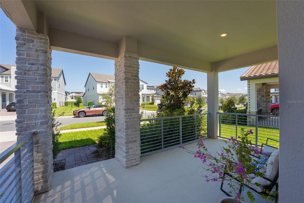 A covered front porch features stone-clad pillars, metal railings, and a view of the street — 5211 CITRUS LEAF BOULEVARD, WINTER GARDEN, FL