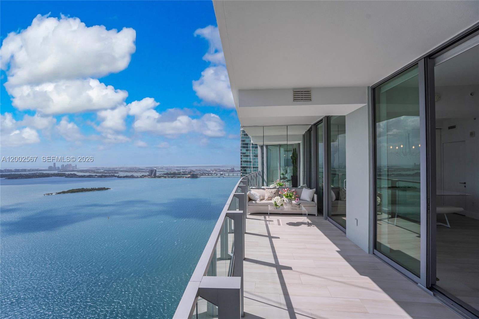 A high-rise balcony features light tile flooring, outdoor seating, and panoramic views of the bay — 2900 NE 7th Ave # 4003, Miami FL 33137, MIAMI, FL