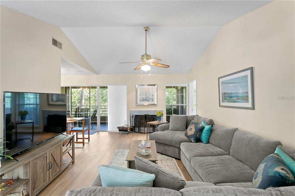A living room features a vaulted ceiling, a gray sectional sofa, and a fireplace — 10823 INDIAN HILLS COURT UNIT 33, SEMINOLE, FL