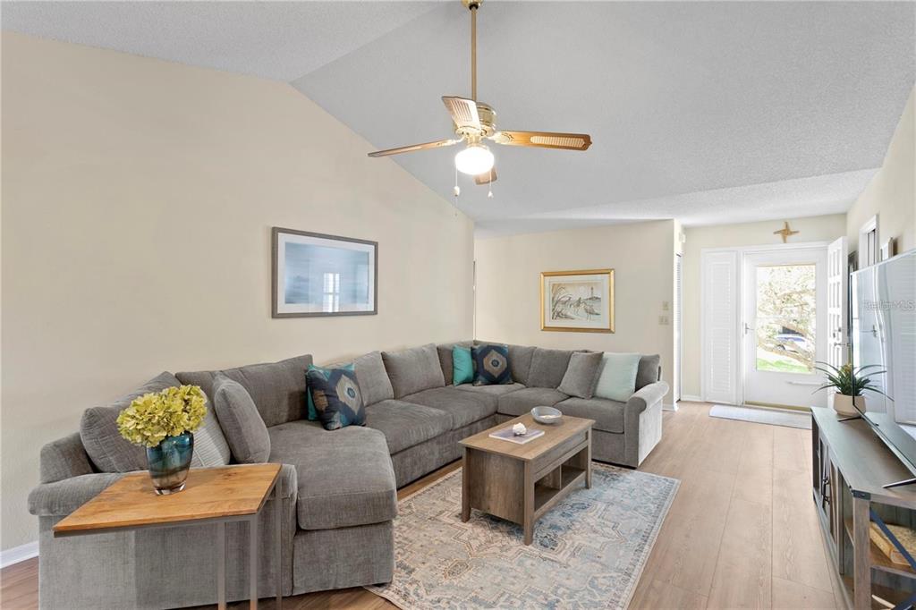 A living room features a large gray sectional sofa, a wooden coffee table, and a ceiling fan — 10823 INDIAN HILLS COURT UNIT 33, SEMINOLE, FL