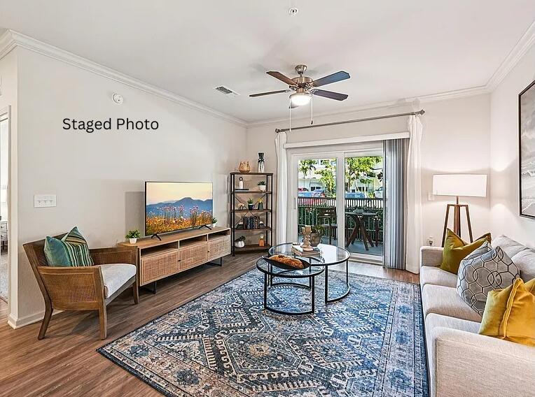 A staged living room features a wooden media console, a patterned rug, and a balcony view — 1900 NW Federal Highway, Stuart FL 34994, STUART, FL