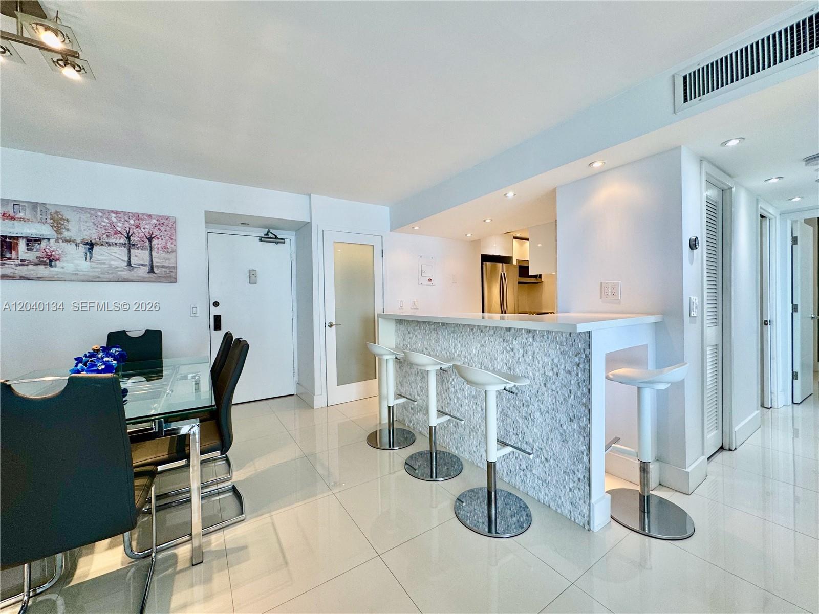 A dining area with a glass table and a kitchen bar with four stools — 200 SE 15th Rd # 9I, Miami FL 33129, MIAMI, FL