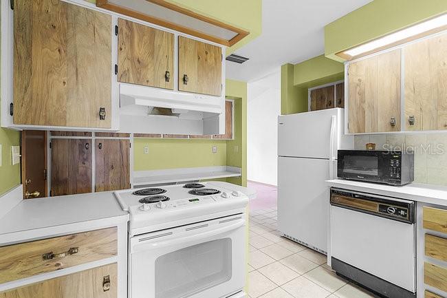 A kitchen features light green walls, white appliances, and wood-paneled cabinets — 7360 CHERRY LAUREL DRIVE, ORLANDO, FL