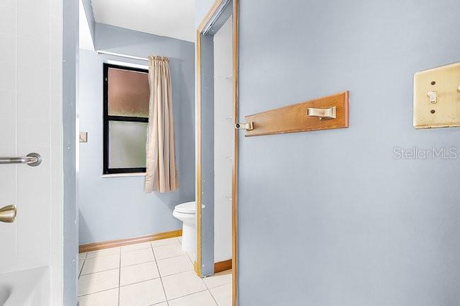 A bathroom features a window with curtains, a white toilet, and a wooden towel rack — 7360 CHERRY LAUREL DRIVE, ORLANDO, FL