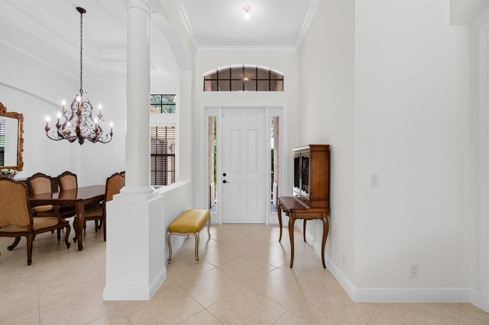 A bright foyer features tile flooring, a white front door, and an adjacent dining area — 15564 Glencrest Avenue, Delray Beach FL 33446, DELRAY BEACH, FL