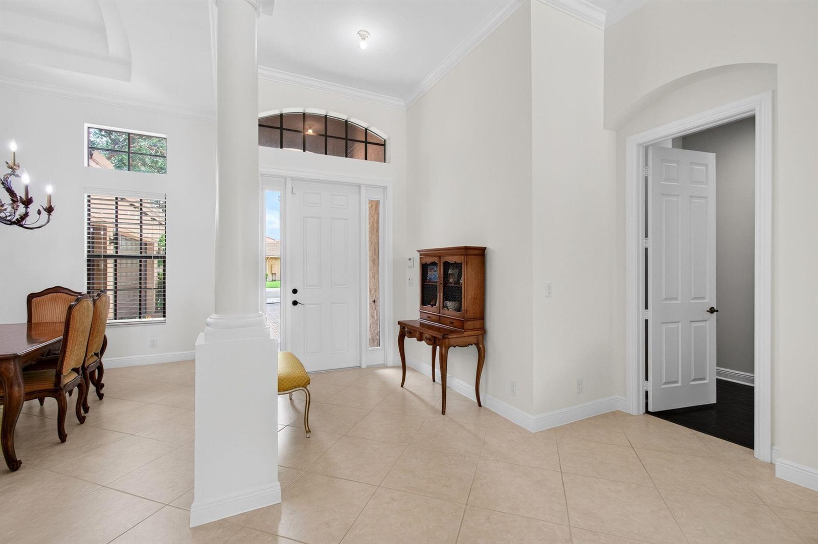 A bright entryway features tile flooring, a white column, a wooden hutch, and a doorway — 15564 Glencrest Avenue, Delray Beach FL 33446, DELRAY BEACH, FL