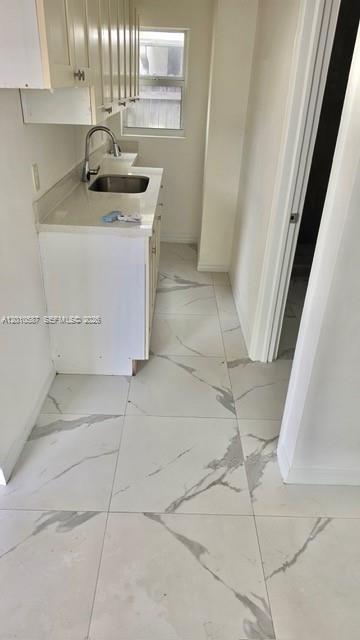 A small kitchen features white cabinets, a stainless steel sink, and white marble-patterned tile flooring — 1718 SW 57th Ave # 1, West Park FL 33023, WEST PARK, FL