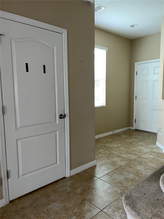 A tiled entryway features a white door on the left and a front door ahead — 1073 PALMA VERDE PLACE, APOPKA, FL