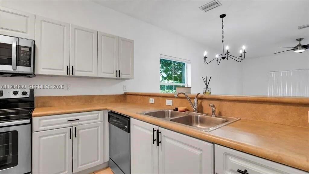 A kitchen features white cabinets, a tan countertop, stainless steel appliances, and a dining area — 4921 SW 140th Ter # 1, Miramar FL 33027, MIRAMAR, FL