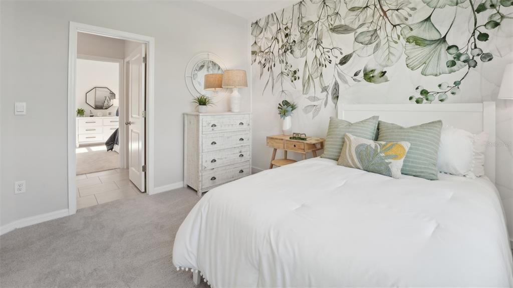 A bedroom features a floral accent wall, a white bed, and a wooden nightstand — 1005 CHASEHILL LANE, ZEPHYRHILLS, FL