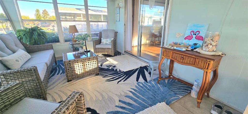This sunroom features wicker furniture, a patterned area rug, and a decorative console table — 176 INDEPENDENCE AVENUE UNIT 6, PALM HARBOR, FL