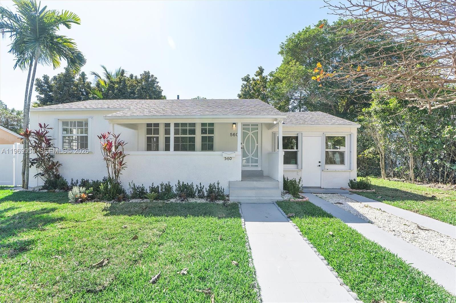 A single-story white house with a front porch, a walkway, and a gravel driveway — 560 NE 110th Ter, Miami FL 33161, MIAMI, FL