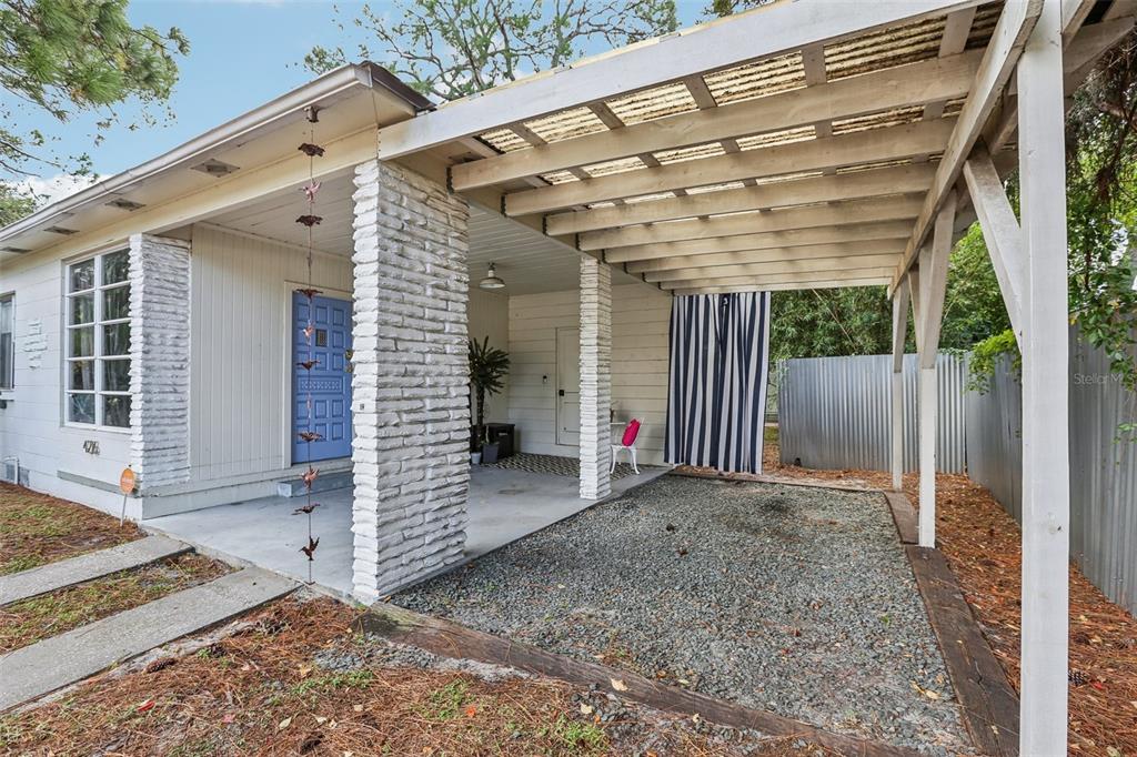 A white house exterior features a covered carport with a gravel floor and brick pillars — 4216 W EUCLID AVENUE, TAMPA, FL