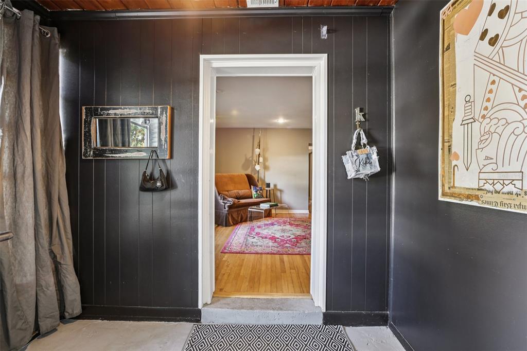 A dark-walled entryway leads through a doorway into a living room with hardwood floors — 4216 W EUCLID AVENUE, TAMPA, FL