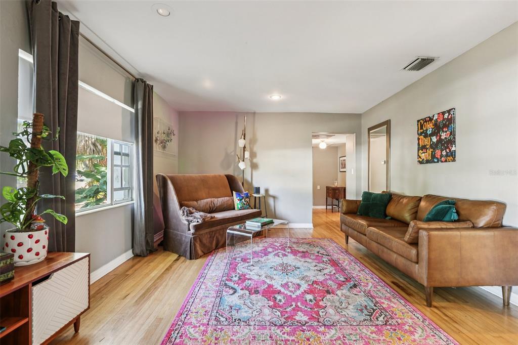 A living room features a brown sofa, a patterned rug, and a large window — 4216 W EUCLID AVENUE, TAMPA, FL