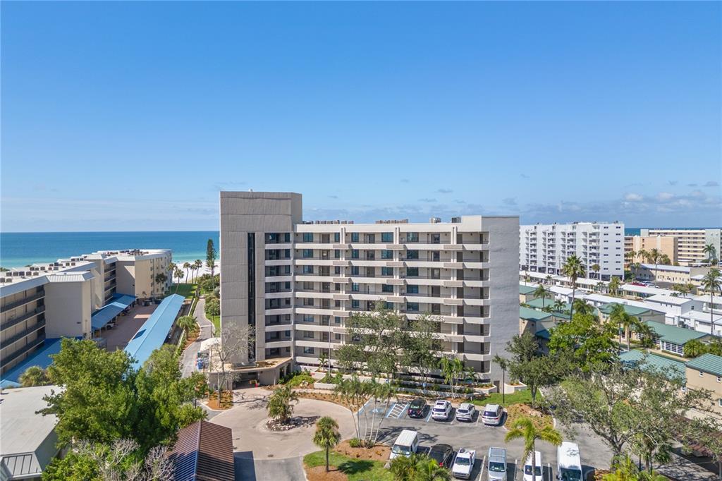 An aerial view shows a multi-story apartment building near a beach with a parking lot — 5880 MIDNIGHT PASS ROAD UNIT 804, SARASOTA, FL