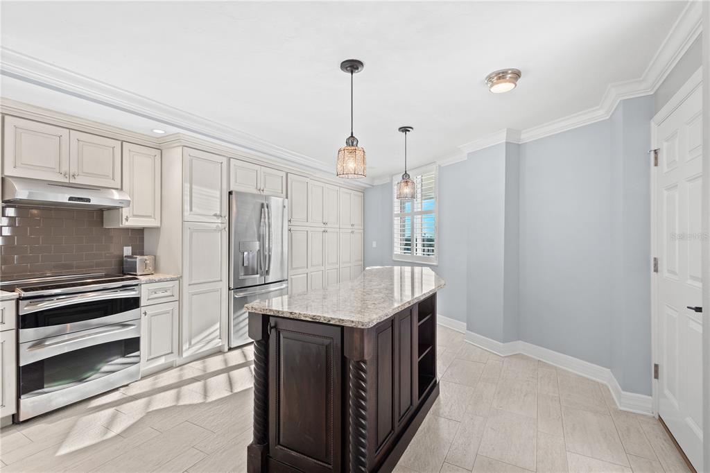 A kitchen with white cabinets, stainless steel appliances, and a dark wood kitchen island — 5880 MIDNIGHT PASS ROAD UNIT 804, SARASOTA, FL