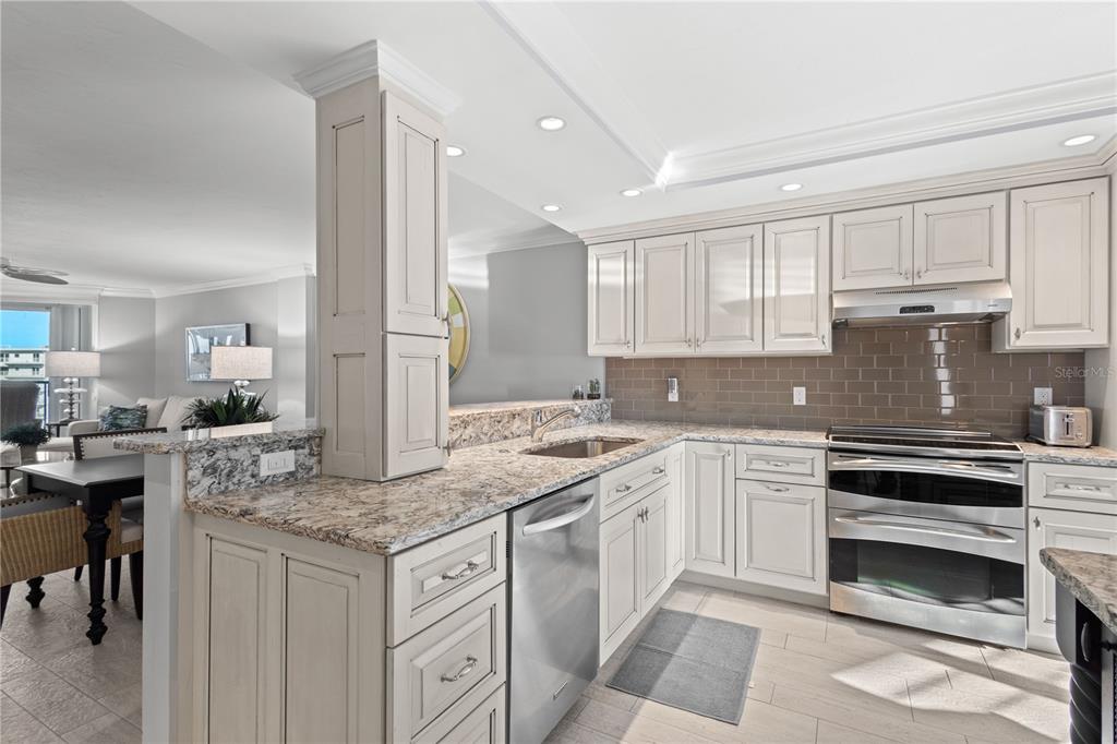 A kitchen with cream cabinets, granite countertops, stainless steel appliances, and a subway tile backsplash — 5880 MIDNIGHT PASS ROAD UNIT 804, SARASOTA, FL