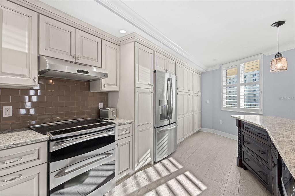 A kitchen with light-colored cabinets, stainless steel appliances, a dark backsplash, and a kitchen island — 5880 MIDNIGHT PASS ROAD UNIT 804, SARASOTA, FL