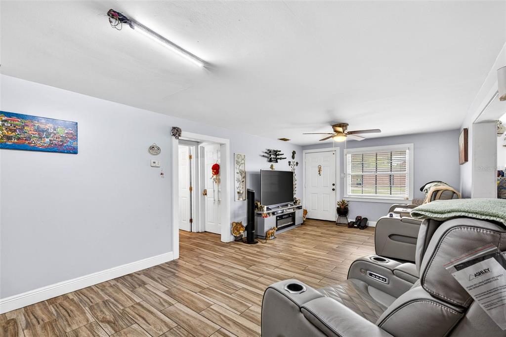 A living room features light gray walls, wood-look tile flooring, a ceiling fan, and a television — 5008 N 17TH STREET, TAMPA, FL