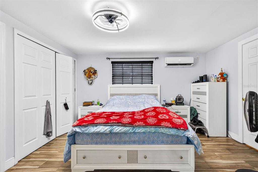 A bedroom features a bed with a red blanket, white furniture, and wood-look flooring — 5008 N 17TH STREET, TAMPA, FL