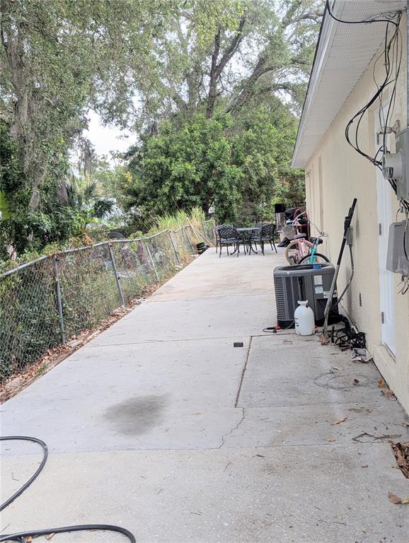 A concrete patio runs along the side of a house next to a chain-link fence — 1808 36TH AVENUE E, BRADENTON, FL