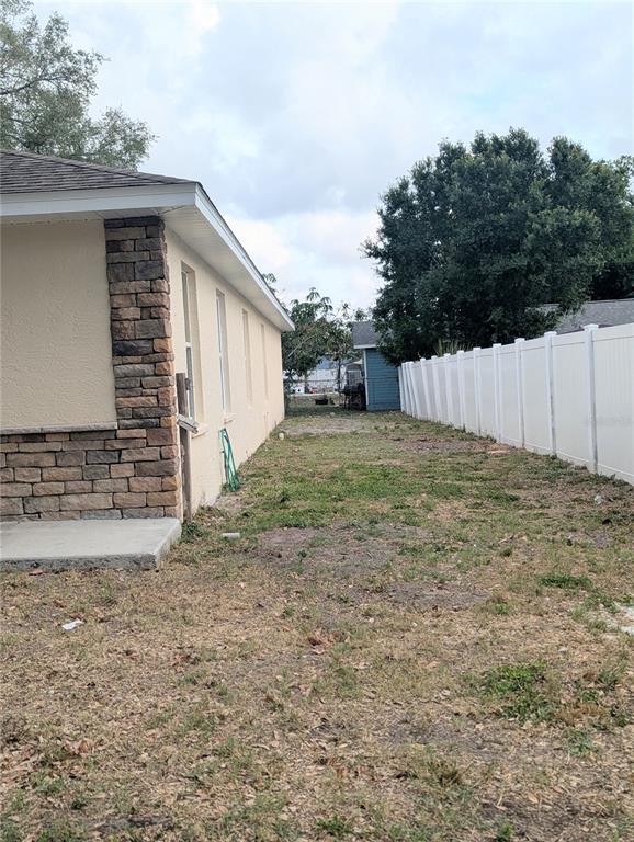 A side view of a house with stone accents and a white vinyl fence — 1808 36TH AVENUE E, BRADENTON, FL