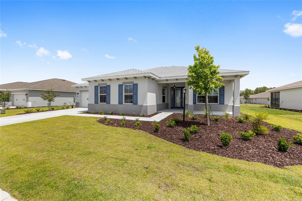 A single-story house with a gray exterior, blue shutters, and a landscaped front yard — 10571 SW 101ST LANE ROAD, OCALA, FL