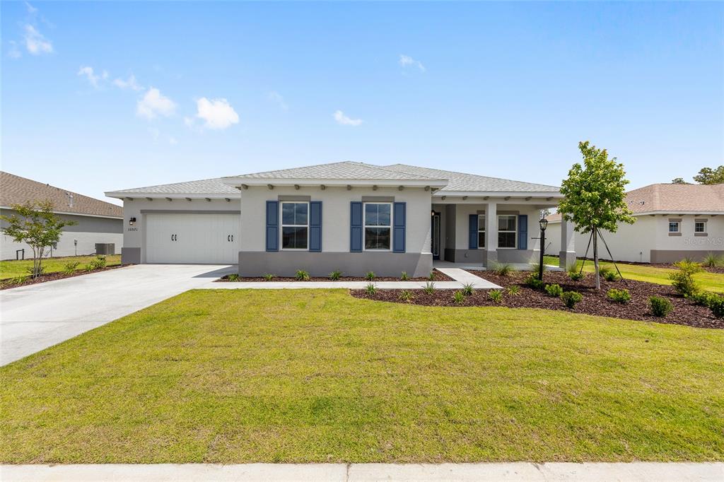 A single-story house with a two-car garage, blue shutters, and a front lawn — 10571 SW 101ST LANE ROAD, OCALA, FL