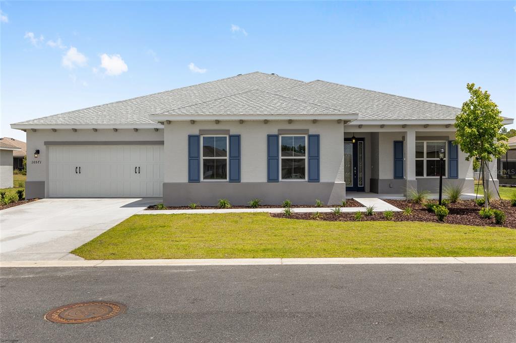 A single-story house with a two-car garage, blue shutters, and a concrete driveway — 10571 SW 101ST LANE ROAD, OCALA, FL