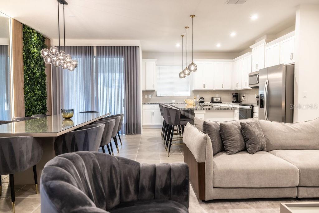 An open-concept living area features a dining space, a modern kitchen, and a gray sofa — 2320 ZABALLINA PLACE, KISSIMMEE, FL
