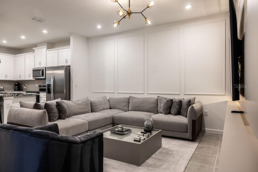 A living room features a grey sectional sofa, a coffee table, and wall molding — 2320 ZABALLINA PLACE, KISSIMMEE, FL