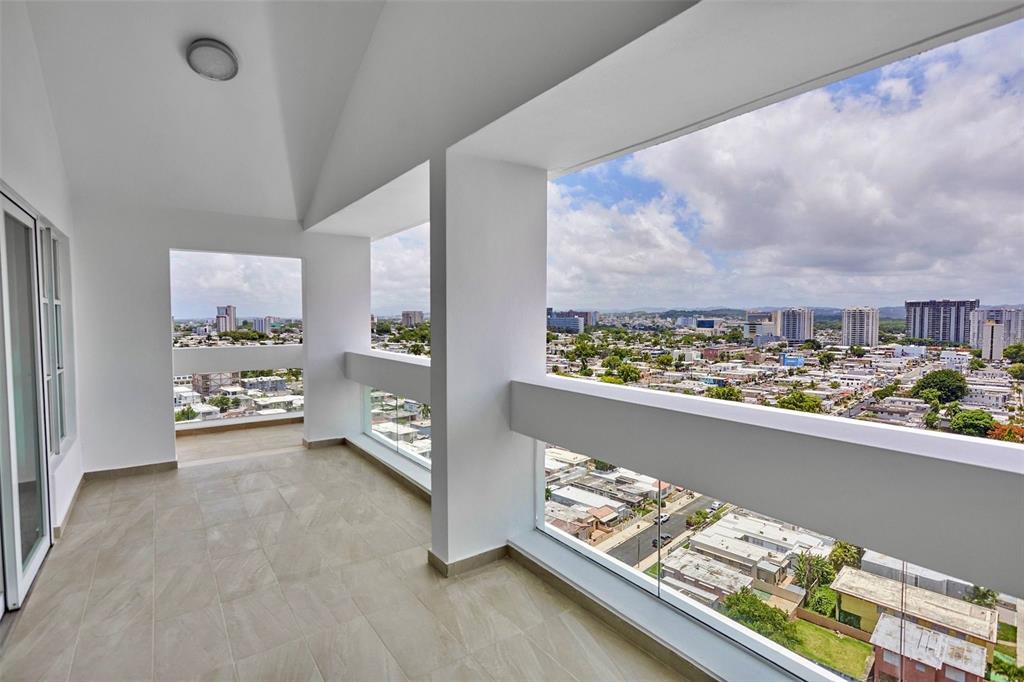 A modern balcony with light tile flooring and glass railings overlooks a sprawling city landscape — 405 CALLE INGENIERO JUAN B. RODRIGUEZ UNIT 1702, SAN JUAN, PR