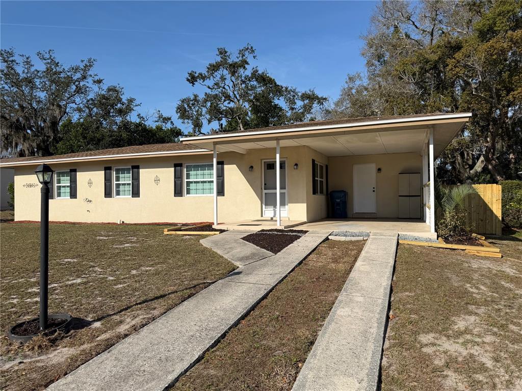 A single-story house with a carport, concrete driveway, and a front yard with trees — 6452 TREEHAVEN DRIVE, SPRING HILL, FL