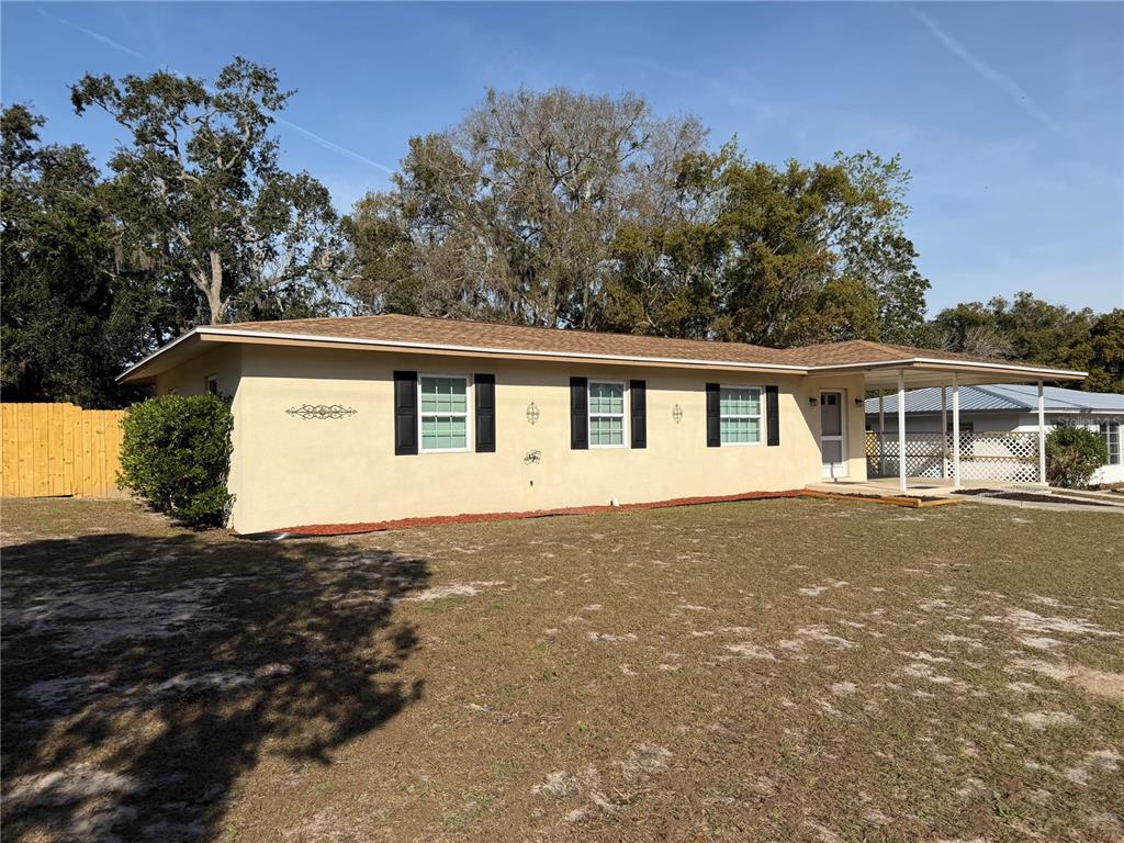 A single-story house with a tan exterior, dark shutters, and a covered side porch — 6452 TREEHAVEN DRIVE, SPRING HILL, FL