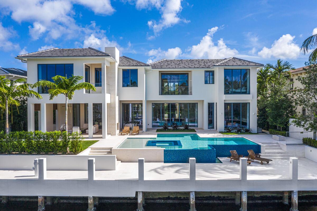 A modern two-story waterfront home features a swimming pool, patio, and large glass windows — 249 W Alexander Palm Road, Boca Raton FL 33432, BOCA RATON, FL