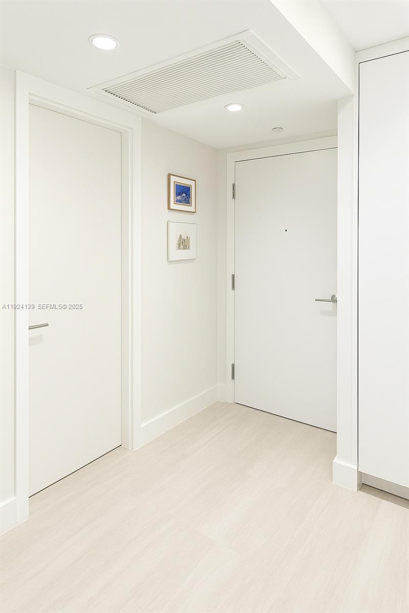 A bright entryway features white walls, light wood-look flooring, and two closed white doors — 2301 Collins Ave # 636, Miami Beach FL 33139, MIAMI BEACH, FL