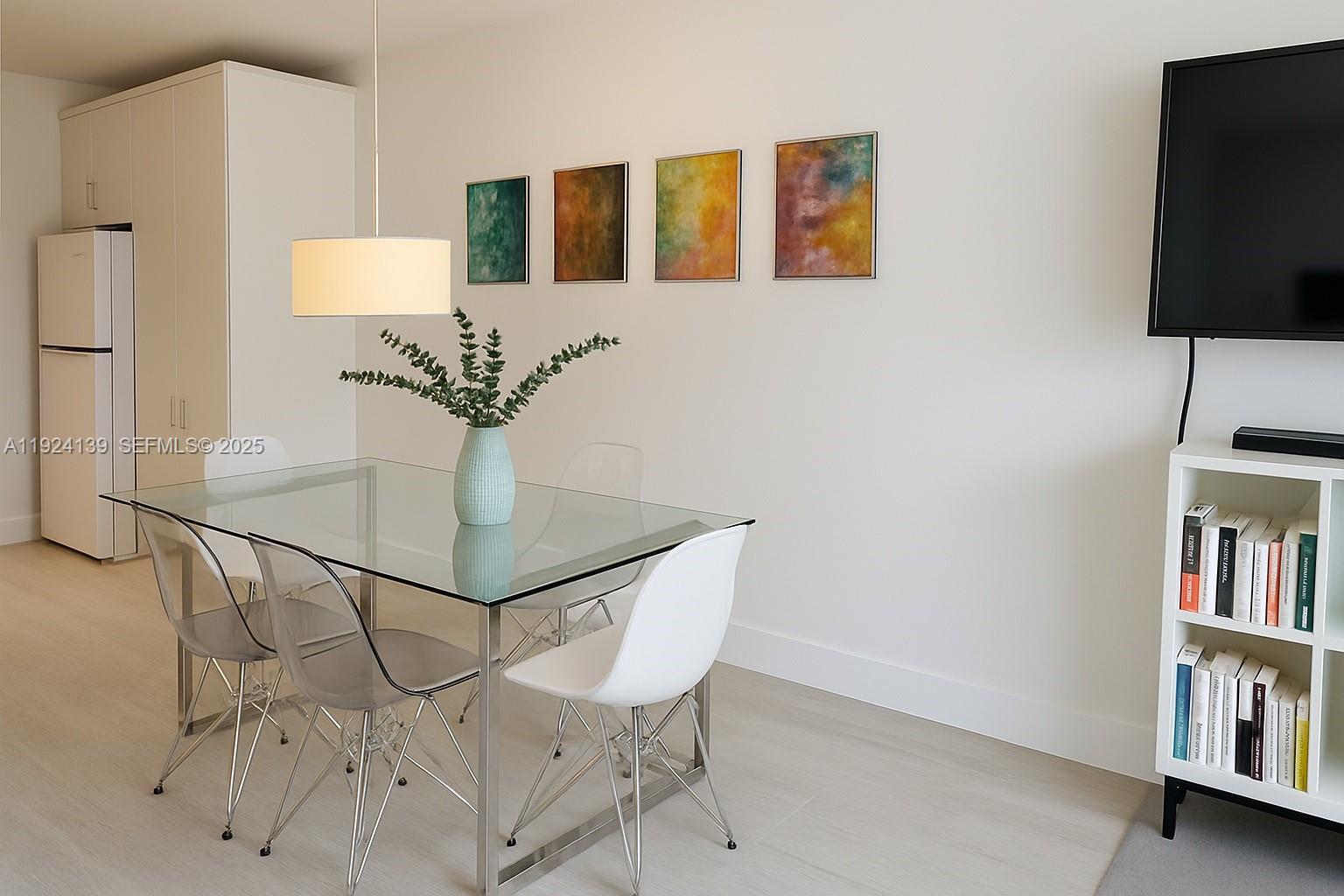 A dining area features a glass table, four chairs, a pendant light, and wall art — 2301 Collins Ave # 636, Miami Beach FL 33139, MIAMI BEACH, FL
