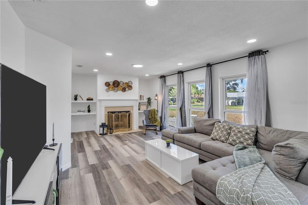 A living room features a fireplace, grey sectional sofa, white coffee table, and wood-look flooring — 1212 63RD STREET NW, BRADENTON, FL