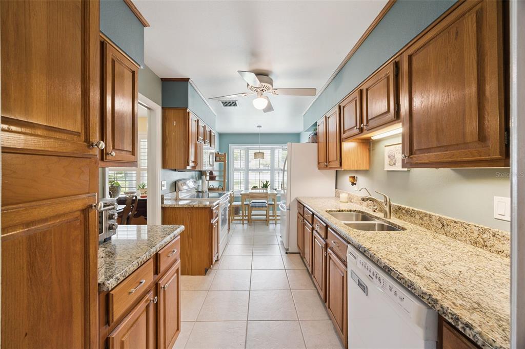 A galley kitchen features wood cabinets, granite countertops, tile floors, and a dining nook — 7923 THURMOND COURT, ORLANDO, FL